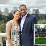 Fita adesiva da cena do crime na frente de uma casa de tijolos de dois andares com telhado escuro e um carro na garagem.