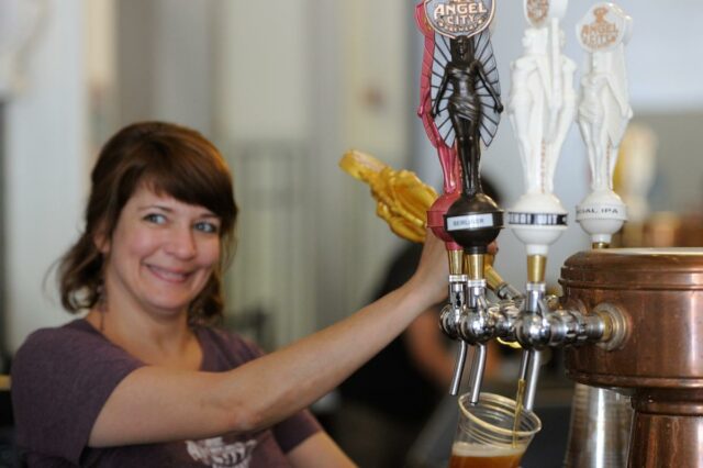 A placa da Angel City Brewery e a placa do Los Angeles Arts District na esquina de um prédio de tijolos.