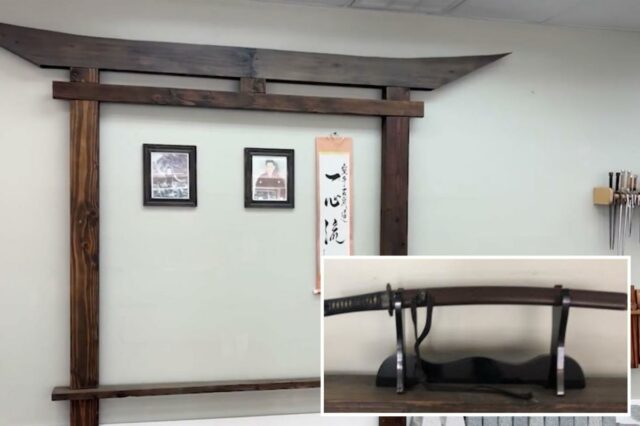 A lendária espada de samurai usada para combate corpo a Espada de samurai histórica com bainha marrom escura apoiada em um suporte preto.