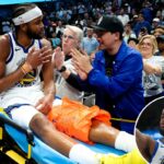 Moses Moody deitado de costas na quadra de basquete, parecendo angustiado.