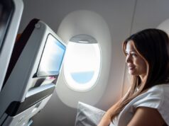 A lista de bagagem de mão de voo épico de uma mulher se torna viral – aqui está o que ela traz Woman watching a video screen on a plane.