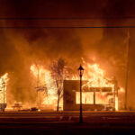 ARQUIVO - Um bombeiro luta contra o incêndio de Palisades enquanto ele queima uma estrutura no bairro de Pacific Palisades, em Los Angeles, 7 de janeiro de 2025. (AP Photo / Ethan Swope, Arquivo)