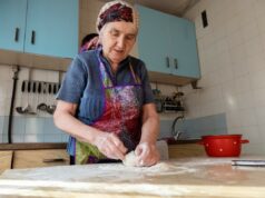 A reviravolta ‘nonna’ na vida na ‘Zona Azul’ pode ser a chave para a longevidade Uma mulher idosa em uma cozinha amassa a massa sobre uma superfície de madeira polvilhada com farinha.