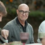 Three men sit at a table outside eating