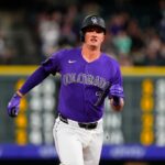 O jogador de beisebol Carter Jensen em uniforme branco com detalhes em roxo e azul, usando um capacete bicolor roxo e azul.
