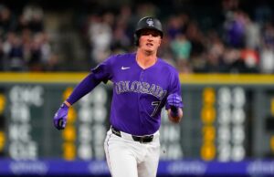 Alvos de isenção de beisebol de fantasia para poder, roubos e ajuda do apanhador O jogador de beisebol Carter Jensen em uniforme branco com detalhes em roxo e azul, usando um capacete bicolor roxo e azul.