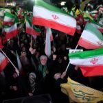 Uma mulher passa por um outdoor gigante onde se lê “O Estreito de Ormuz permanece fechado” na Praça da Revolução em Teerã, Irã, em 12 de abril de 2026.