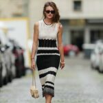 PARIS, FRANÇA - 22 DE ABRIL: Alba Garavito Torre usa brincos de ouro, um macacão Mirae verde com padrão de margaridas brancas com pescoço com nó e tornozelos inchados, uma jaqueta blazer longa branca, uma pulseira de ouro e strass, anéis de ouro, uma pulseira APM Monaco rosa ouro, uma bolsa Le Chiquito média Jacquemus de couro branco brilhante, tiras de couro branco fosco Bottega Veneta sandálias de salto alto, em 22 de abril, 2021 em Paris, França. (Foto de Edward Berthelot/Getty Images)