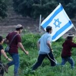 Colonos israelenses caminham em direção à fronteira Israel-Gaza durante uma manifestação perto do Kibutz Kfar Aza, no sul de Israel, em 5 de fevereiro de 2026.