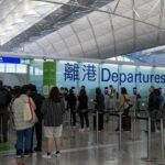 Os viajantes fazem fila no Aeroporto Internacional de Hong Kong.