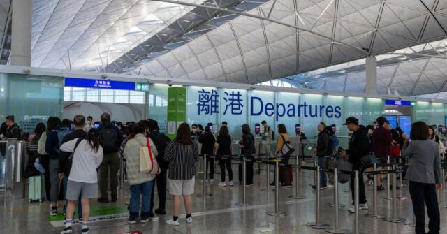 Os viajantes fazem fila no Aeroporto Internacional de Hong Kong.