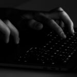 Apple alerta usuários de iPhone em 100 países que são vítimas de spyware | Foto assustadora e discreta em preto e branco de mãos digitando em um teclado