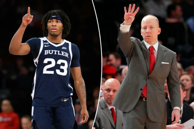 Um jogador de basquete vestindo uma camisa azul escura do Butler com o número 23 aponta o dedo indicador direito para cima.