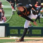 Um arremessador de beisebol com uniforme preto e laranja no meio da entrega.