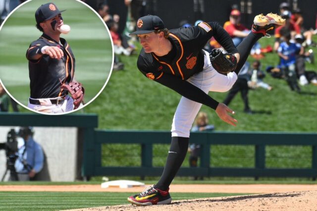 Um arremessador de beisebol com uniforme preto e laranja no meio da entrega.