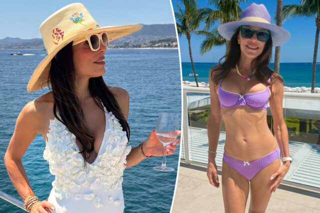 Bethenny Frankel parada no oceano usando um biquíni roxo e chapéu de sol.