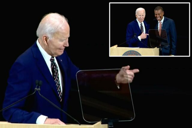 Biden exige desajeitadamente que um curador da Universidade de Syracuse Joe Biden aponta para um pódio ao lado de um homem rindo.