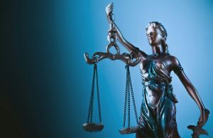 CFTC processa Wisconsin por crescente regulamentação do mercado de luta contra previsão Uma estátua da Senhora Justiça segurando balanças em frente a um fundo azul.