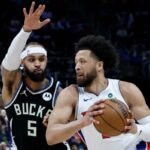 O guarda estrela que retorna Cade Cunningham dirige sobre Gary Trent Jr. de Milwaukee durante o jogo Piston-Bucks em 8 de abril de 2026 em Detroit.