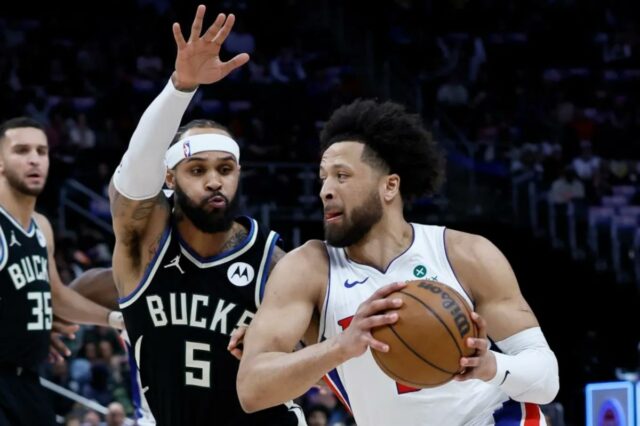 O guarda estrela que retorna Cade Cunningham dirige sobre Gary Trent Jr. de Milwaukee durante o jogo Piston-Bucks em 8 de abril de 2026 em Detroit.