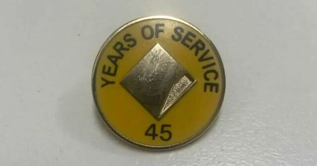 Um homem afirma que sua mãe recebeu este distintivo e flores por 45 anos de serviço no Commonwealth Bank.