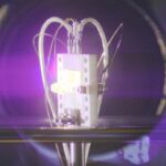 A radiovoltaic material glows under bombardment by alpha particles.