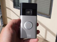 Compre uma campainha com vídeo Ring por apenas US $ 14 Uma campainha com câmera branca montada ao lado de uma porta branca, encostada em uma parede vermelha ousada com padrões geométricos.