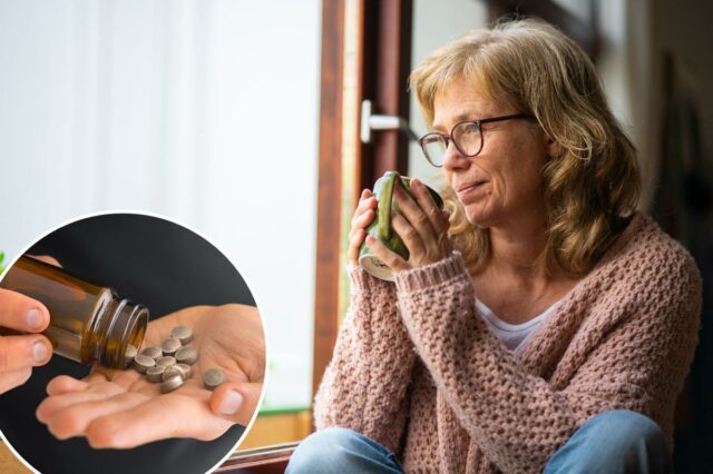 Uma mulher mais velha, loira e de óculos, toma um gole de chá, olhando pensativamente pela janela.