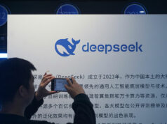 DeepSeek apresenta novo modelo de IA que ‘fecha a lacuna’ com modelos de fronteira A man takes photos of a DeepSeek display at a shopping mall in Hangzhou