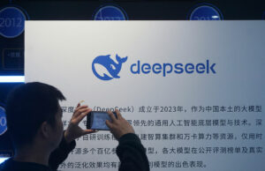DeepSeek apresenta novo modelo de IA que ‘fecha a lacuna’ com modelos de fronteira A man takes photos of a DeepSeek display at a shopping mall in Hangzhou