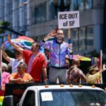 O legislador estadual democrata Scott Weiner, sem camisa, com colete de couro e gravata preta, em uma rua da cidade.