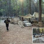 Uma pessoa com equipamento de proteção e máscara de gás caminha por uma clareira na floresta com lonas, barracas e tanques, indicando um laboratório de drogas e um acampamento.