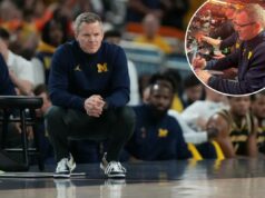 Dusty May estava na quadra observando UConn-Illinois antes do jogo Final Four de Michigan O técnico do Michigan, Dusty May, assiste ao jogo do lado de fora, agachado.