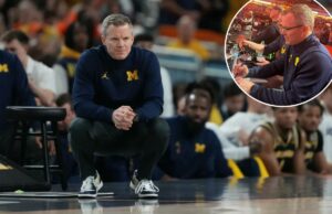 Dusty May estava na quadra observando UConn-Illinois antes do jogo Final Four de Michigan O técnico do Michigan, Dusty May, assiste ao jogo do lado de fora, agachado.