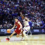 O guarda do St. John's Red Storm, Dylan Darling, driblando a bola contra um jogador do Kansas Jayhawks.