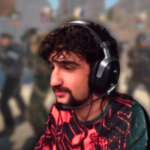 Jogador profissional de esportes eletrônicos usando fone de ouvido jogando jogo de tiro Counter-Strike com fundo de equipe tática desfocado durante uma partida competitiva. ESIC bane jogador de Counter-Strike Nifee por violações de manipulação de resultados