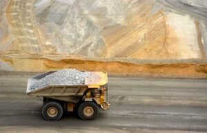 Earth AI está integrando verticalmente a busca por minerais críticos A large yellow dump truck carries ore out of a pit mine.