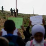 Khalil e Tareq seguram faixa com crianças (Jacob Lazarus/Al Jazeera)