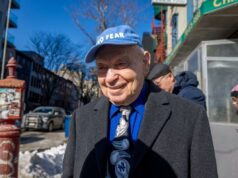 Esnobado por Mamdani, sobrevivente do Holocausto espera pelo milagre da Páscoa Sami Steigmann com boné e terno azuis, sorrindo