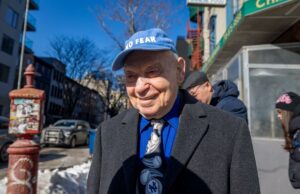 Esnobado por Mamdani, sobrevivente do Holocausto espera pelo milagre da Páscoa Sami Steigmann com boné e terno azuis, sorrindo