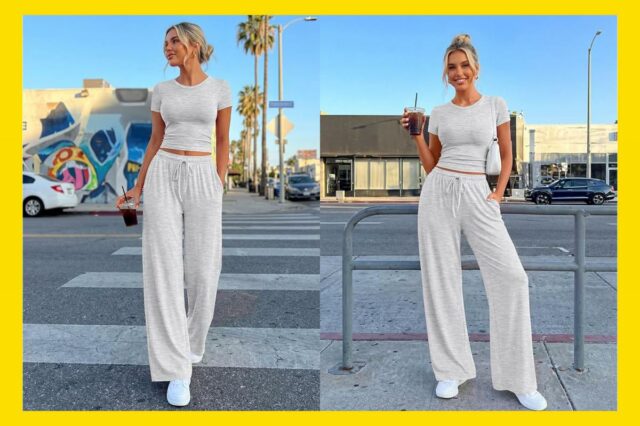 Uma mulher vestindo um top cinza claro de mangas curtas e calças largas combinando, segurando uma bebida e uma bolsa de ombro branca.