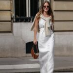 Alba Garavito Torre usa brincos de ouro e pérolas, um colar de pérolas brancas, uma camisa branca com padrão de folha de árvore verde, calças de terno rosa claro, anéis de ouro, um anel verde, um anel rosa, uma pulseira Love Cartier de ouro, pulseiras de ouro, uma bolsa Chiquito Medium Jacquemus de couro branco, sapatos Manolo Blahnik de cetim verde escuro, em 23 de maio de 2021 em Paris, França.