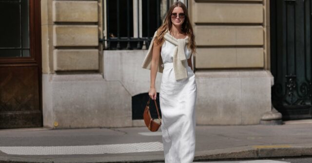 Alba Garavito Torre usa brincos de ouro e pérolas, um colar de pérolas brancas, uma camisa branca com padrão de folha de árvore verde, calças de terno rosa claro, anéis de ouro, um anel verde, um anel rosa, uma pulseira Love Cartier de ouro, pulseiras de ouro, uma bolsa Chiquito Medium Jacquemus de couro branco, sapatos Manolo Blahnik de cetim verde escuro, em 23 de maio de 2021 em Paris, França.