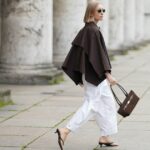 HAMBURGO, ALEMANHA - 17 DE AGOSTO: Laura Noltemeyer é vista vestindo um suéter de malha texturizado grande e solto em bege da Aylin Koenig; estilizado por baixo com um vestido plissado metálico transparente da H&M; combinado com mocassins de camurça cinza da Birkenstock. Ela está carregando uma bolsa Hermès estruturada esbranquiçada com detalhes e alças em couro marrom escuro; complementado com óculos de sol retangulares pretos de acetato da Saint Laurent; o cabelo é repartido ao meio e penteado em um rabo de cavalo baixo e elegante em 17 de agosto de 2025 em Hamburgo, Alemanha. (Foto de Moritz Scholz/Getty Images)