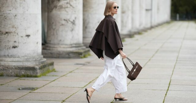 HAMBURGO, ALEMANHA - 17 DE AGOSTO: Laura Noltemeyer é vista vestindo um suéter de malha texturizado grande e solto em bege da Aylin Koenig; estilizado por baixo com um vestido plissado metálico transparente da H&M; combinado com mocassins de camurça cinza da Birkenstock. Ela está carregando uma bolsa Hermès estruturada esbranquiçada com detalhes e alças em couro marrom escuro; complementado com óculos de sol retangulares pretos de acetato da Saint Laurent; o cabelo é repartido ao meio e penteado em um rabo de cavalo baixo e elegante em 17 de agosto de 2025 em Hamburgo, Alemanha. (Foto de Moritz Scholz/Getty Images)