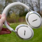 Fones de ouvido Bose QuietComfort Ultra no estojo, sustentados pela folhagem de outono ao fundo
