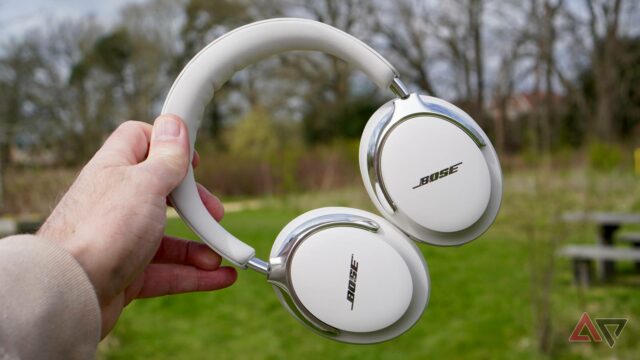Fones de ouvido Bose QuietComfort Ultra no estojo, sustentados pela folhagem de outono ao fundo