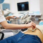 Médico realizando um ultrassom abdominal em um paciente.