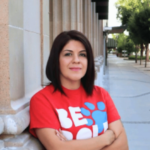 O ex-gerente do Fresno Arts Council admite roubo de US$ 1,8 milhão em despesas de jogo. Suliana Caldwell com uma camiseta vermelha encostada em um prédio