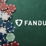 FanDuel aprovado para expansão da rede de pôquer multiestadual no mercado de Michigan. Logotipo FanDuel na mesa de pôquer verde com fichas de cassino vermelhas, brancas e azuis, empilhadas em fundo de feltro